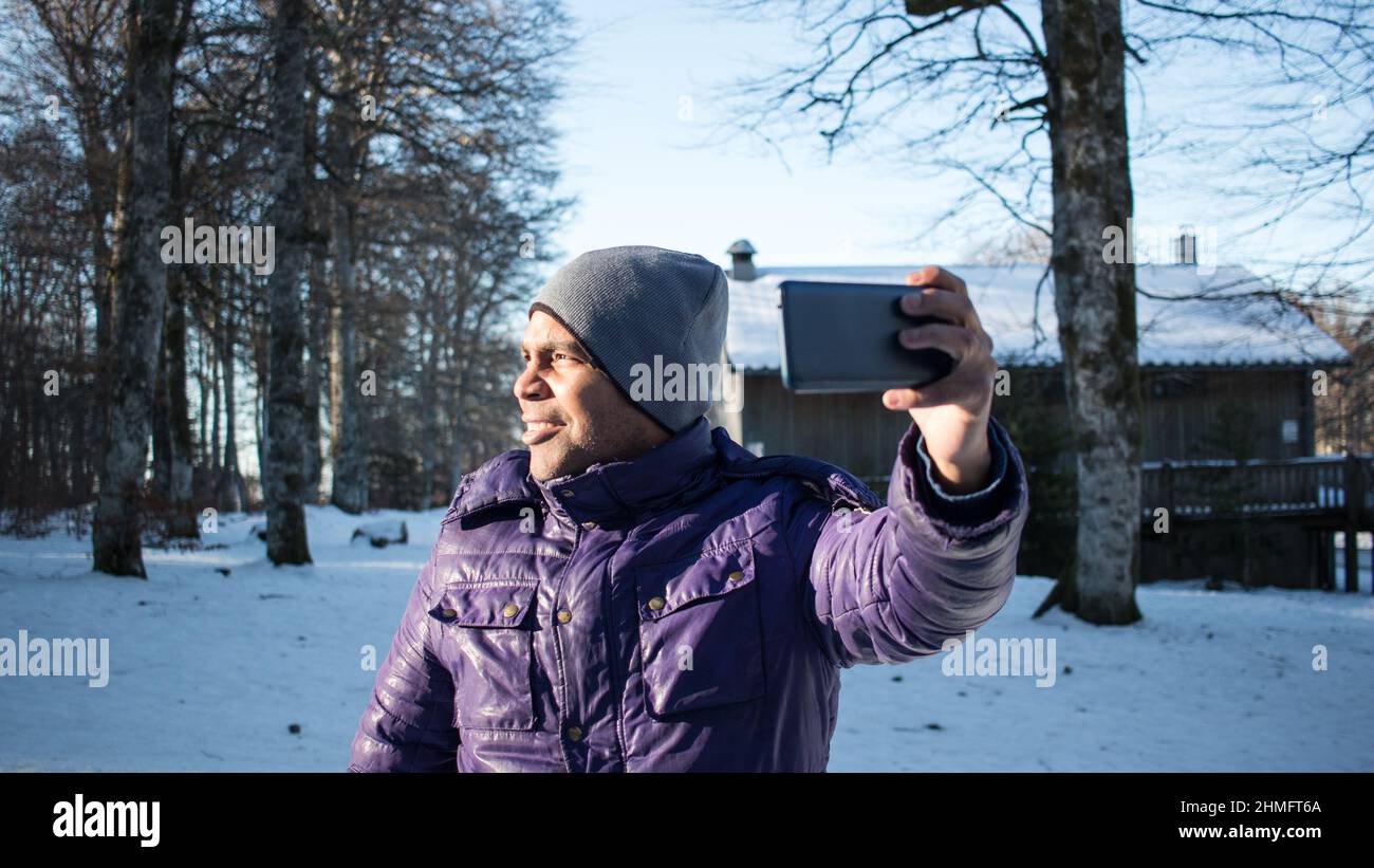 Gros plan sur un jeune homme en vacances dans la neige emportant un selfie avec son smartphone Banque D'Images