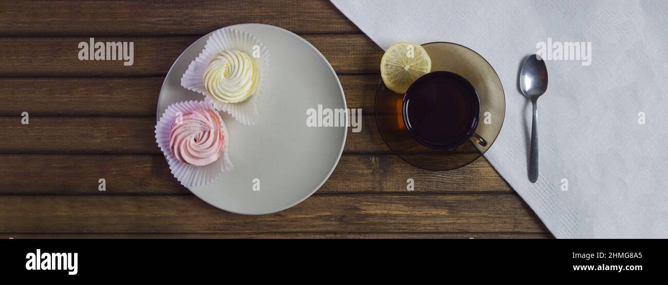 Zephyr sur plaque. Concept de cadeau de vacances. Aliments nocifs pour les diabétiques, faible concentration. Tasse de thé avec citron et cuillère sur serviette blanche. Décoration de table pour de Banque D'Images