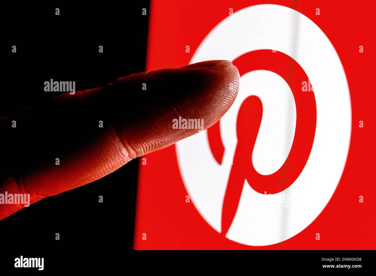 Le doigt atteint le logo du service de médias sociaux Pinterest sur l'écran du smartphone. Banque D'Images