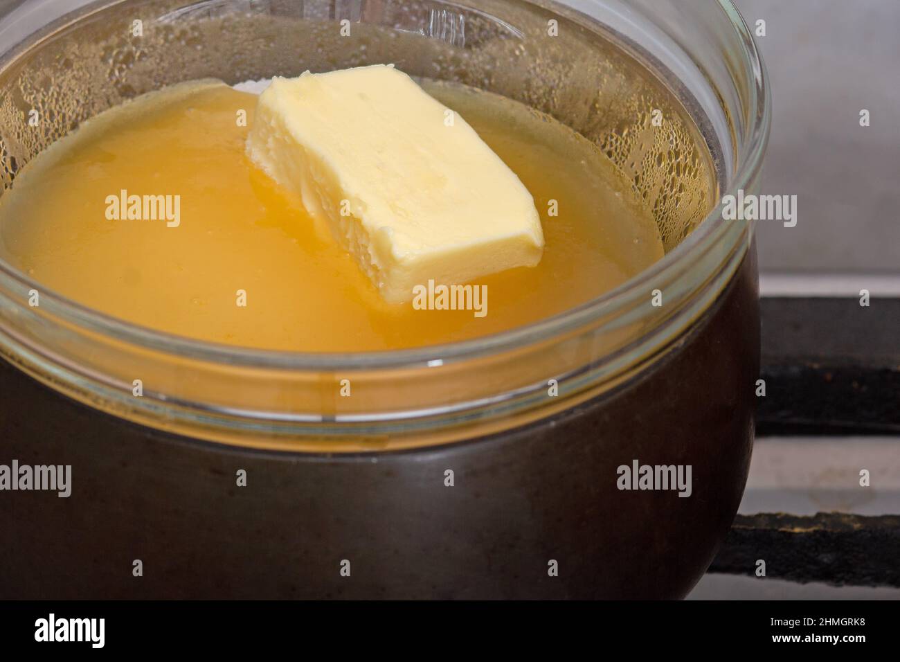 Bain-marie avec le sucre, le beurre et le miel dans un bol en verre sur une  casserole comme ingrédients du gâteau medovik sur la plaque de cuisson  Photo Stock - Alamy