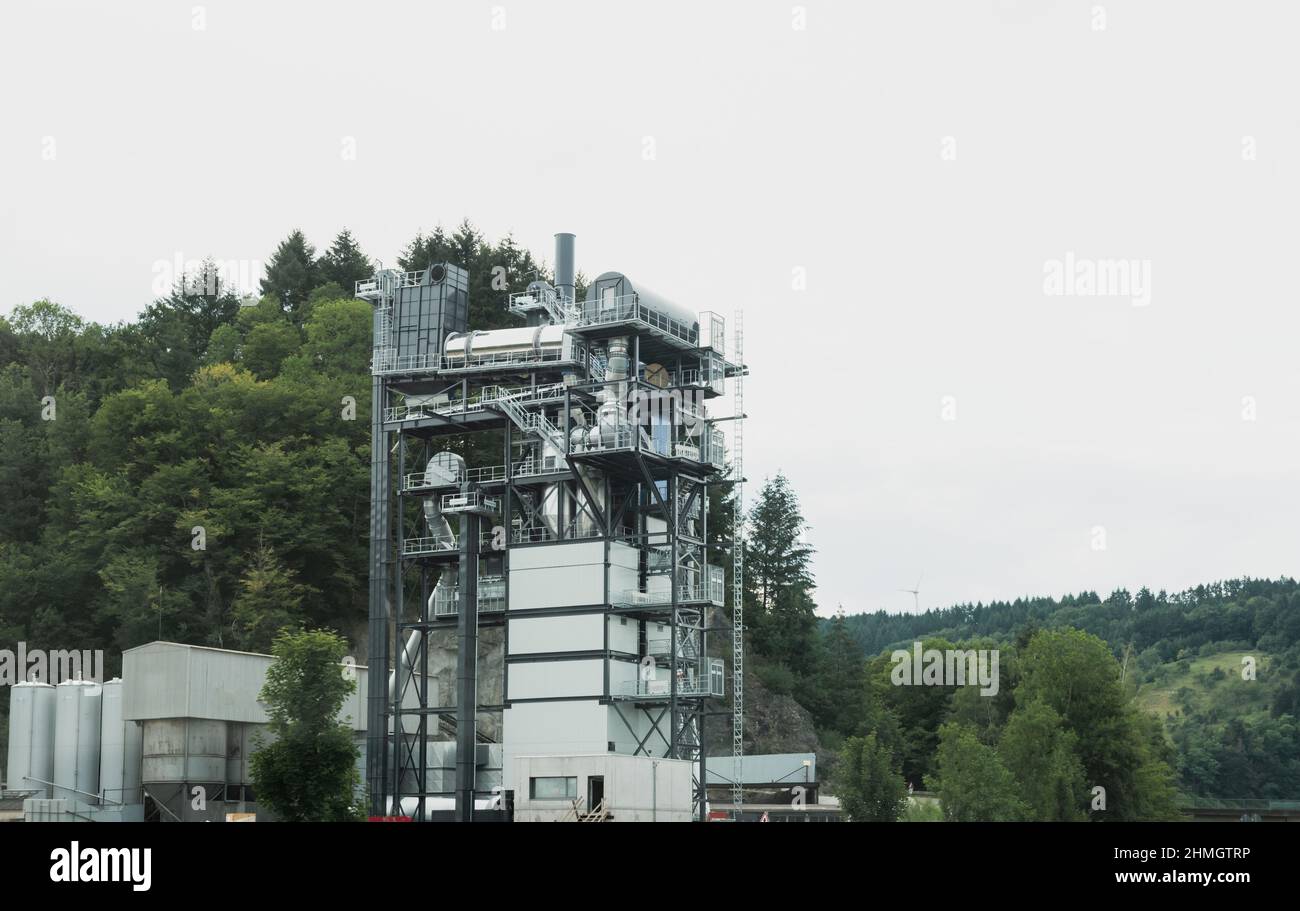 Usine générique de recyclage de matériaux de construction avec de hautes forêts en arrière-plan - tuyaux de matériaux de transformation en asphalte et autres produits bons - respectueux de l'environnement Banque D'Images