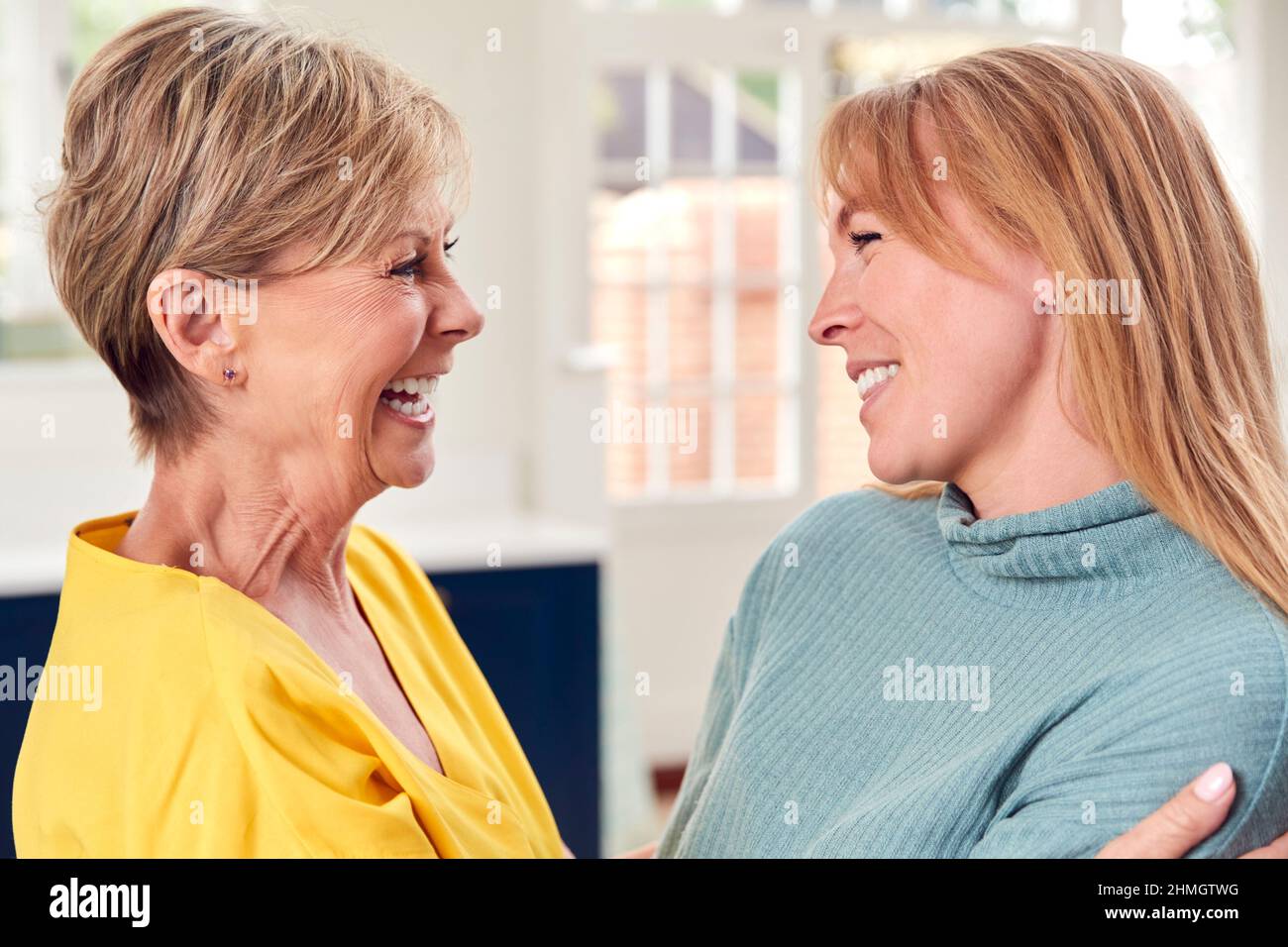 Femme aînée saluant et embrassant une fille adulte à la maison Banque D'Images