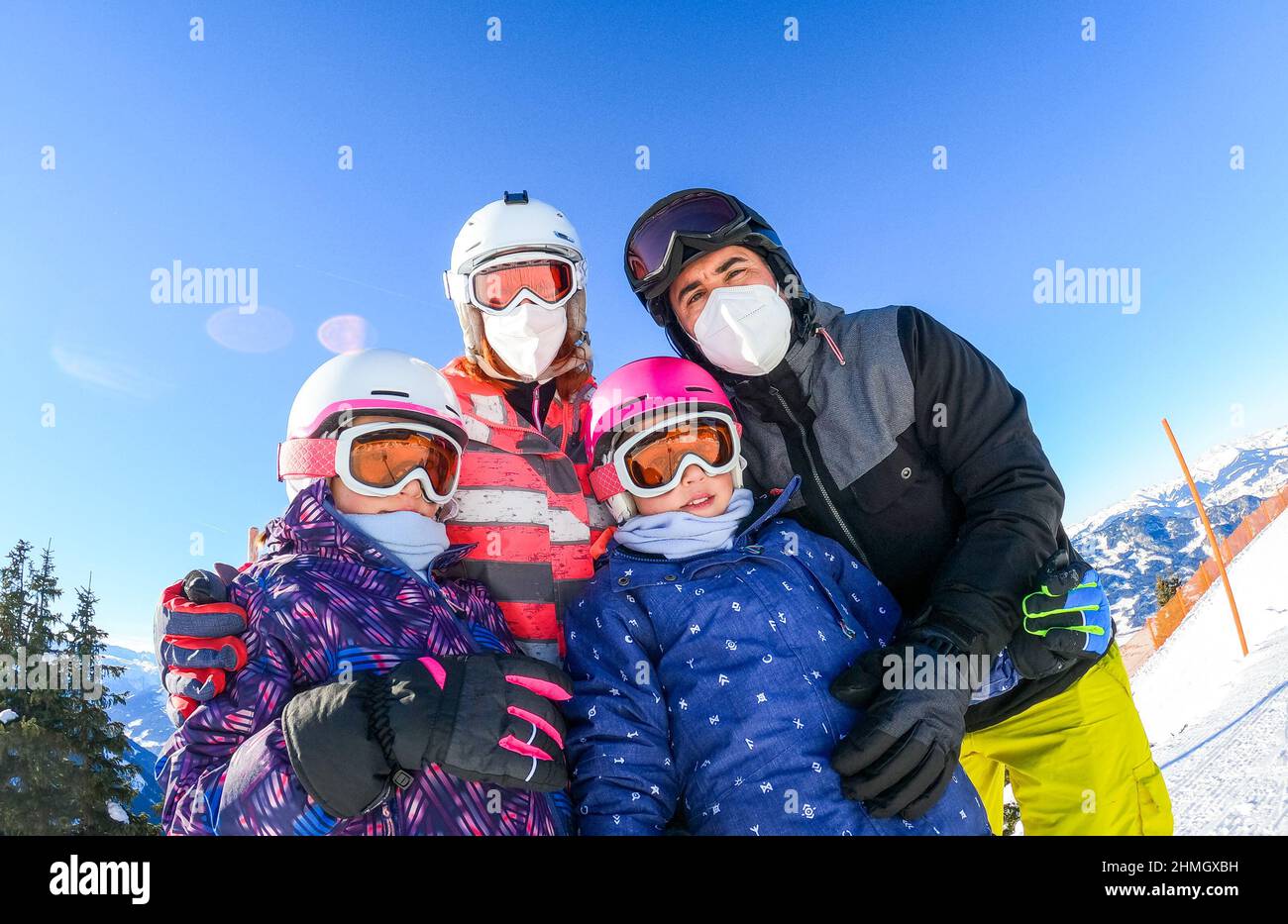 Famille profitant de vacances d'hiver en équipement de ski portant des masques. Famille avec enfants en vacances de ski vêtus de matériel de ski avec casques et porte-skis Banque D'Images