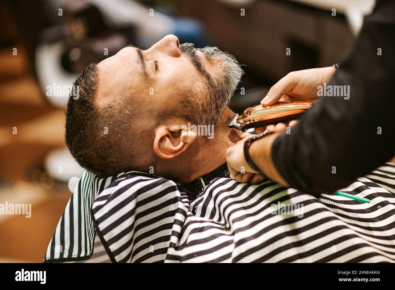 Barber tond la barbe du client dans son salon de coiffure dans un concept de beauté et de soin Banque D'Images