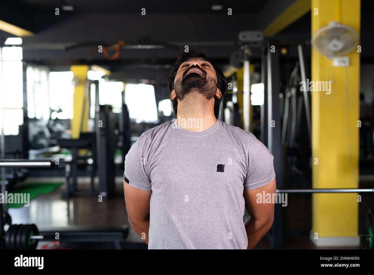jeune homme occupé à faire la rotation du cou exercice d'échauffement à la salle de gym - concept de bien-être, style de vie sain et séance d'entraînement Banque D'Images