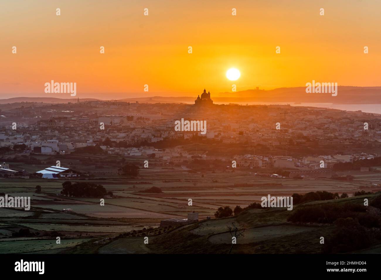 Le dernier jour de l'année, le soleil du matin se lève juste derrière la basilique de Goza, Malte, baignant le paysage en lumière dorée. Banque D'Images