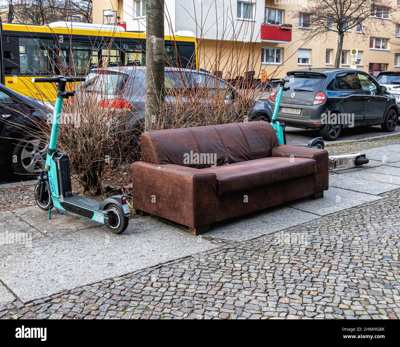 Jeté, abandonné, jeté, canapé en cuir et e-trottinettes électriques sur la chaussée à Gesundbrunnen, Berlin Banque D'Images