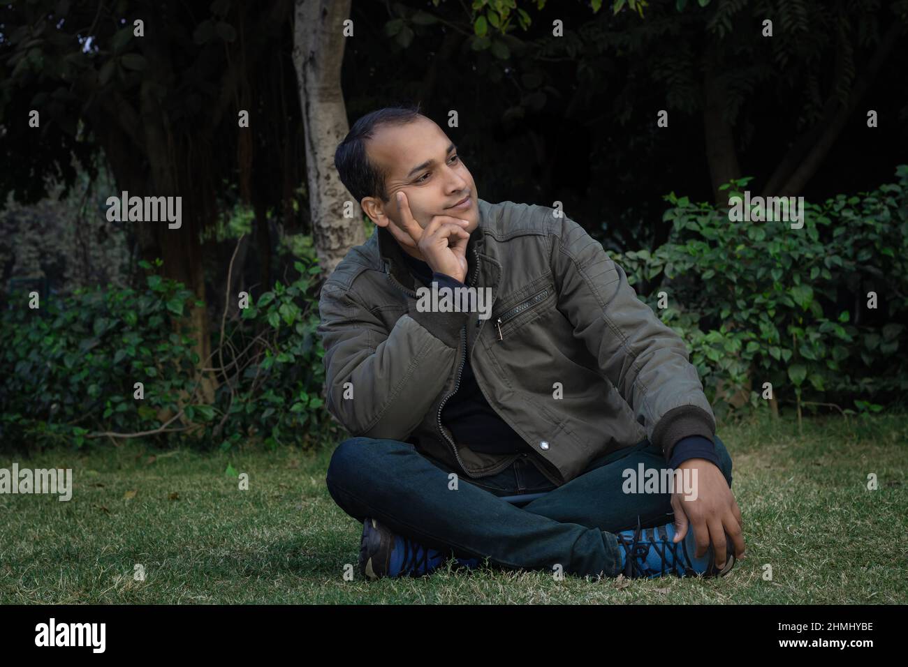 jeune homme différentes humeurs d'expression crossent la jambe assis dans un parc à partir d'un angle plat Banque D'Images