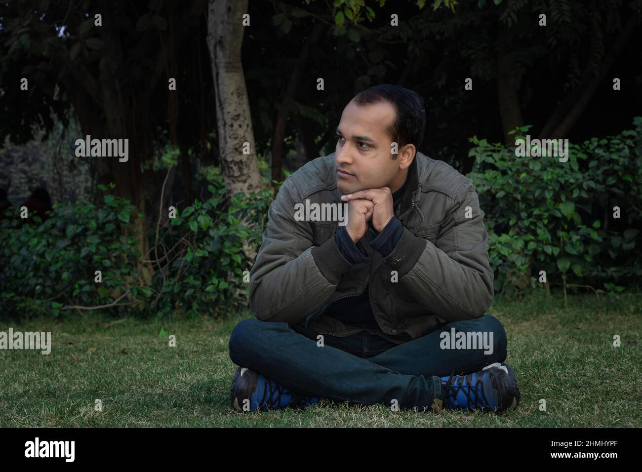 jeune homme différentes humeurs d'expression crossent la jambe assis dans un parc à partir d'un angle plat Banque D'Images