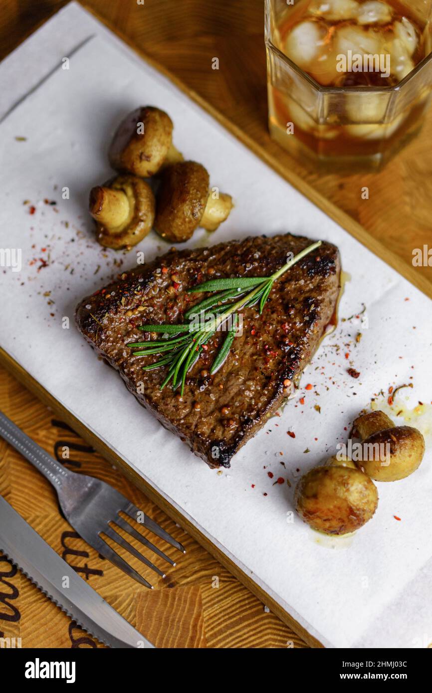 Viandes fraîches grillées. Steak de bœuf moyen rare avec brunch au romarin et mashrooms sur planche à découper en bois Banque D'Images