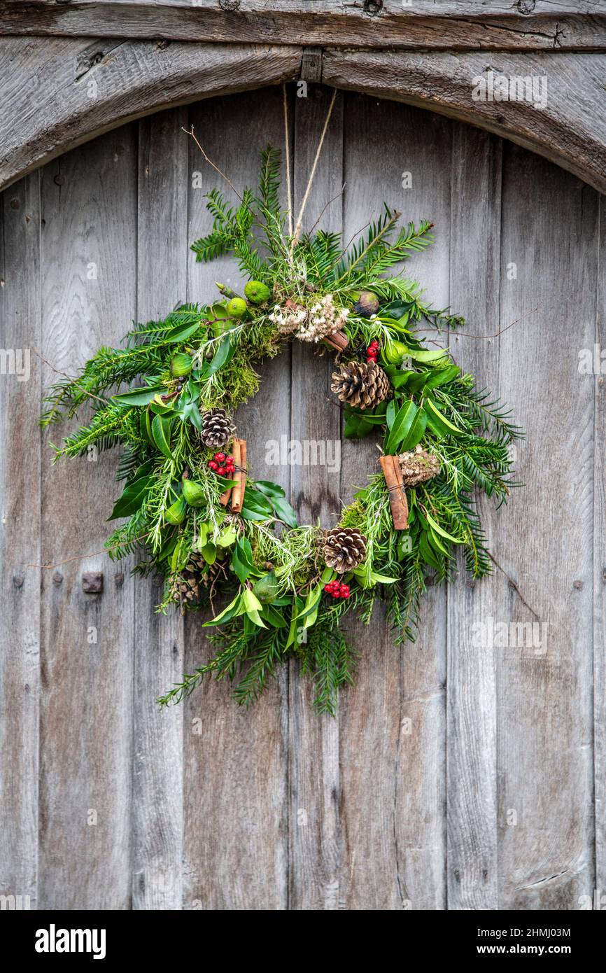 Couronne de Noël avec des cônes de pin, des feuilles et des brindilles sur une porte en bois (Ashwell, Hertfordshire, Royaume-Uni) Banque D'Images