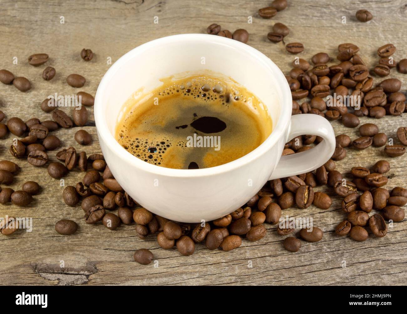 Une tasse de café et de grains de café sur une planche à bois Banque D'Images