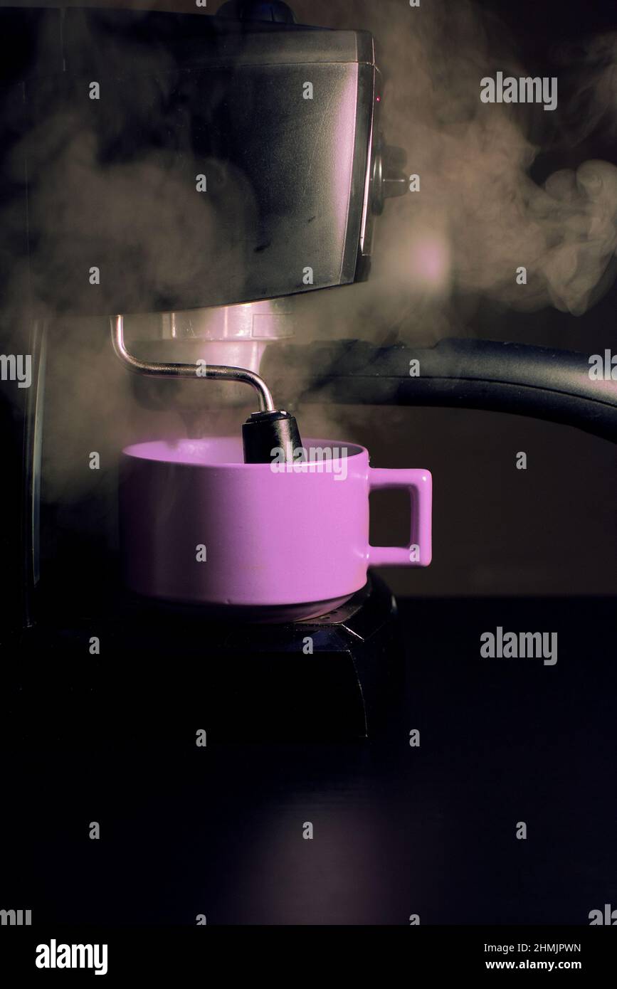 Gros plan d'une tasse à café mauve et d'une machine à expresso entourée de vapeur Banque D'Images