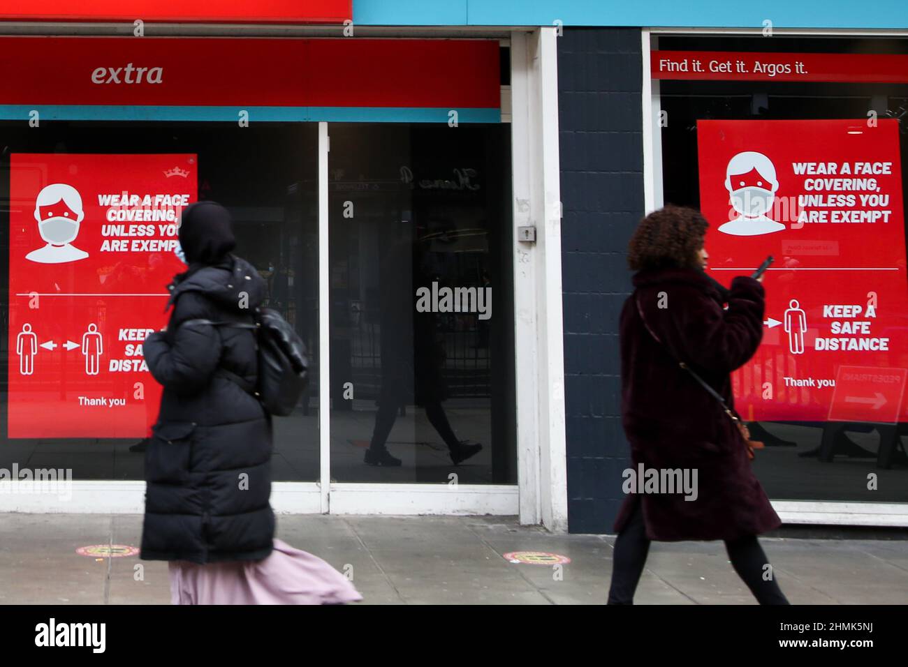 Londres, Royaume-Uni. 10th févr. 2022. Les femmes marchent devant une affiche « porter un visage couvert à moins que vous ne soyez exonéré » affichée dans une vitrine de magasin.le Premier ministre, Boris Johnson, a annoncé qu'il présentera le plan du gouvernement pour vivre avec Covid-19 lorsque le Parlement reviendra d'un court séjour le 21 février, Toutes les restrictions Covid-19 doivent être mises au rebut. Crédit : SOPA Images Limited/Alamy Live News Banque D'Images