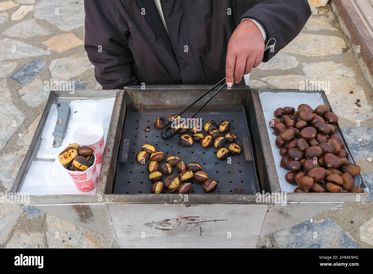 Homme vendant à la main des châtaignes traditionnelles dans une rue, des châtaignes fraîchement cuites de la cuisine turkısh, marché de rue, cuisine turque et concept de cuisine. Banque D'Images