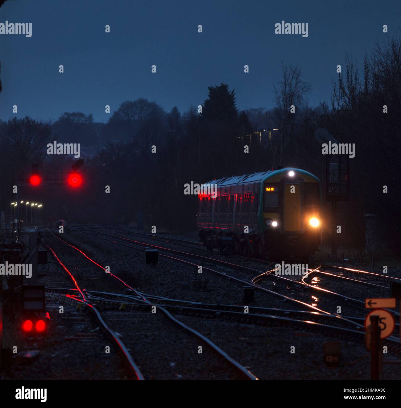 London midland Bombardier classe 172 avec ses phares qui glinent sur la piste et des signaux rouges à la jonction de Stourbridge lors d'une nuit sombre et humide Banque D'Images