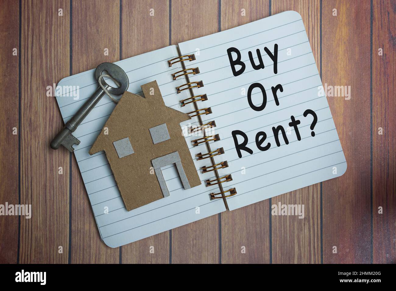 Acheter ou louer une question sur un livre de notes avec modèle de maison et clé sur un bureau en bois. Investissement immobilier et concept commercial Banque D'Images