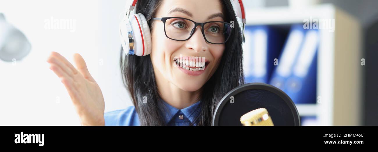 Femme présentatrice de la radio avec casque parlant dans le microphone en studio Banque D'Images