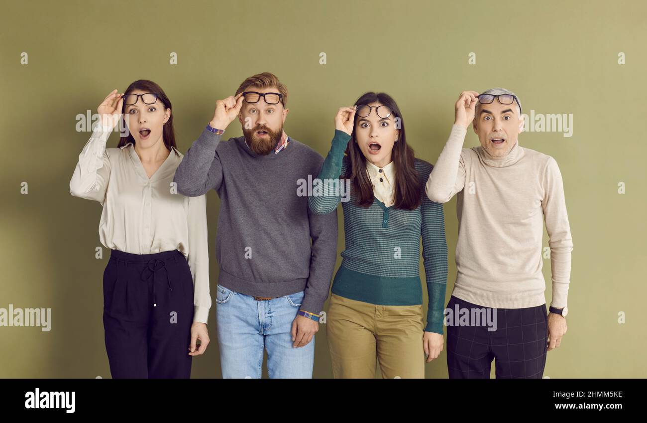 Quatre personnes prennent leurs lunettes lorsqu'elles voient quelque chose de surprenant et de choquant Banque D'Images