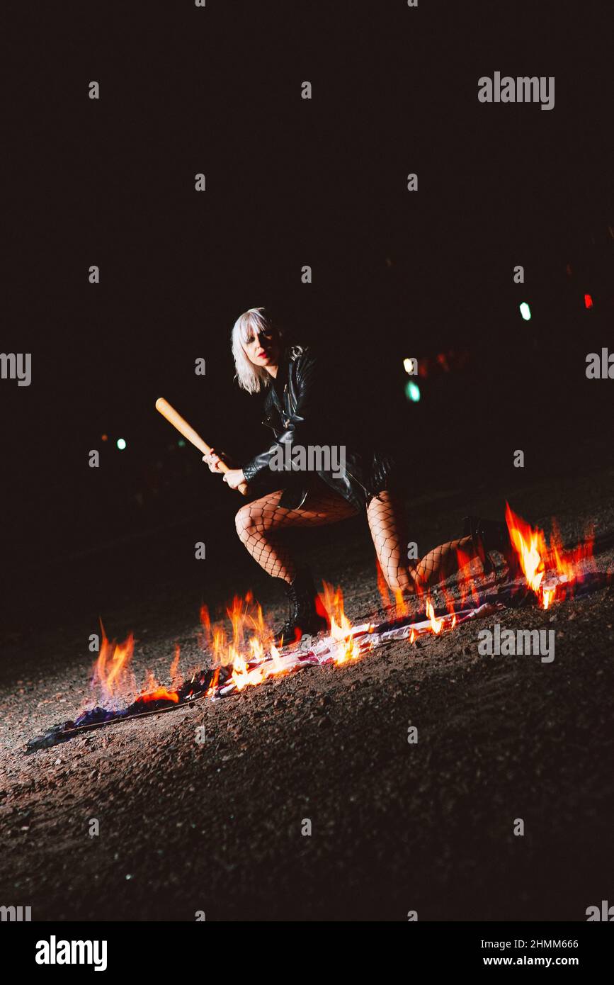 Portrait de la jeune femme blonde élégante grunge avec le club près du feu Banque D'Images