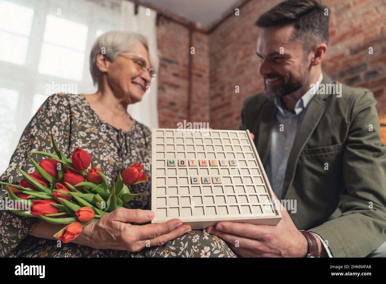 Assiette de fête des mères tenue par son fils millénaire d'âge moyen et sa mère âgée déplacée . Photo de haute qualité Banque D'Images