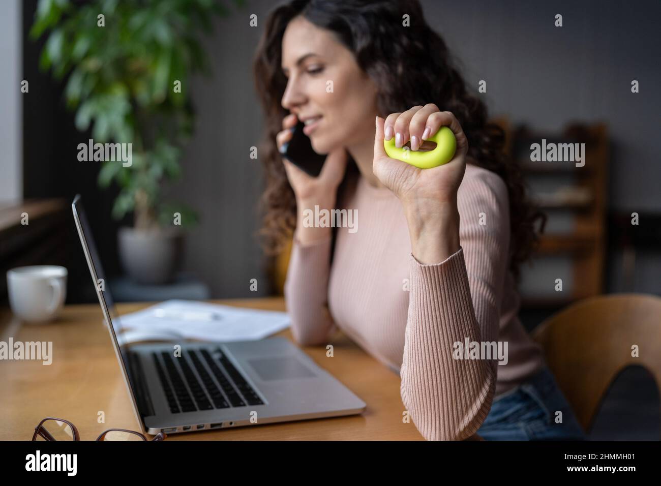 Une femme atteinte du syndrome du canal carpien s'exerçant avec un anneau de force de préhension sur le lieu de travail Banque D'Images