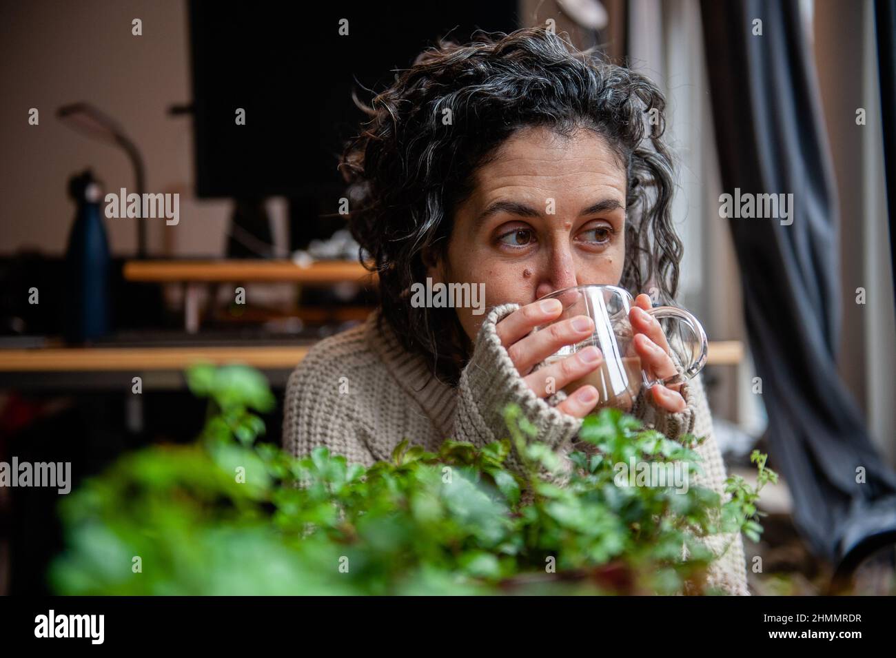 On voit une femme prendre une tasse de café tout en portant un chandail chaud.la Journée du chandail chaud est organisée chaque année un vendredi de février par le 'Klimaatverbond Nederland' (Climate Association Netherlands), une association d'organisations publiques avec des ambitions dans le domaine de la durabilité et du changement climatique. Il s'agit d'une action nationale sur le climat qui consiste à ce que tous les participants s'engagent à baisser le chauffage dans leurs foyers, leurs bureaux et leur lieu de travail, ou dans leurs salles de classe. Au lieu de chauffer l'espace, ils se réchauffent en portant un pull confortable, confortable et chaud. Pays-Bas cou Banque D'Images