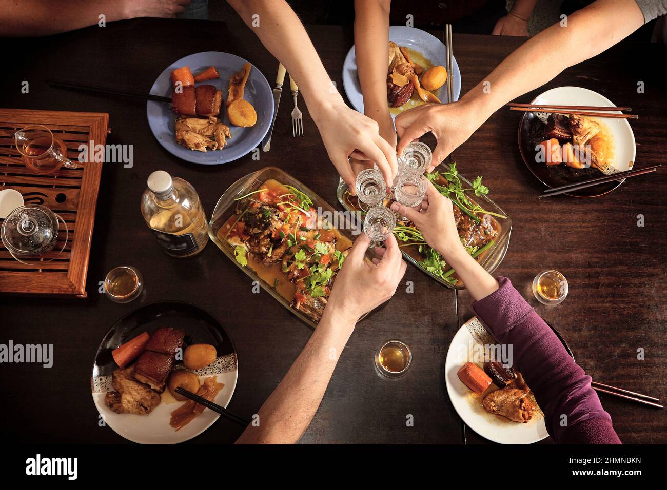 Dîner avec des amis à la table. Vue de dessus. Cuisine chinoise avec baguettes. Poisson, viande, porc, pommes de terre. Banque D'Images