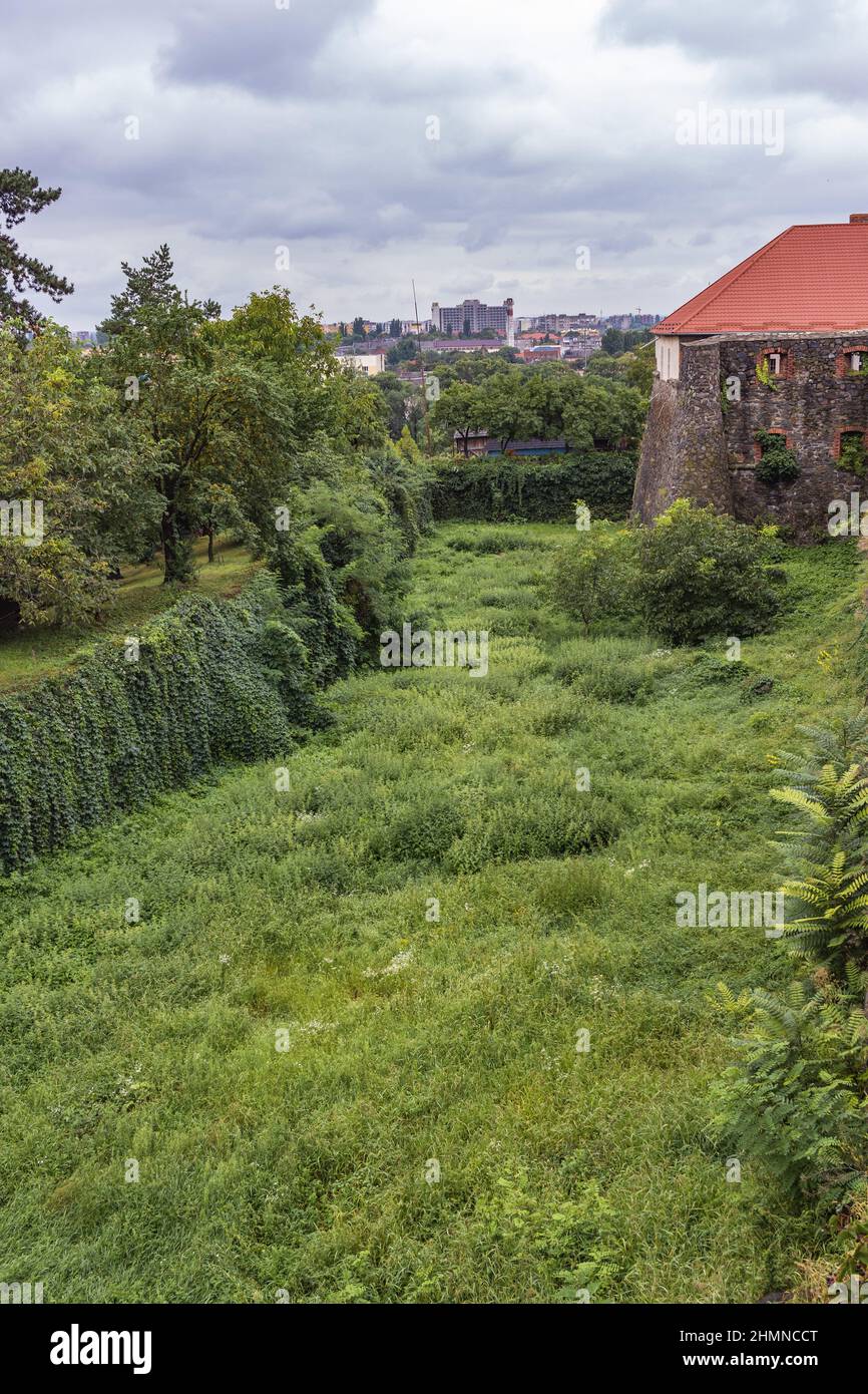 Mur médiéval du château gris de l'ancien château d'Uzhgorod avec une pelouse verte devant. Château d'Uzhgorod, région de Zakarpattya, Ukraine occidentale Banque D'Images