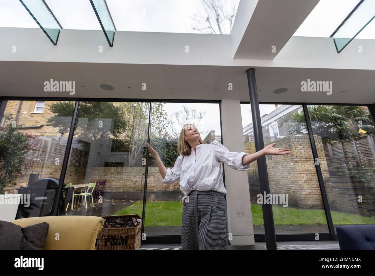 Femme regardant le plafond en verre dans son extension de conservatoire résidentiel, Angleterre, Royaume-Uni Banque D'Images