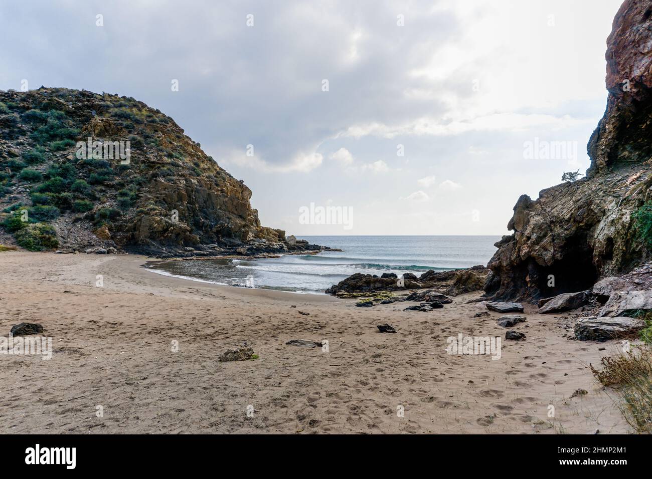 Une plage de sable isolée sur une côte montagneuse sauvage avec des rochers Banque D'Images