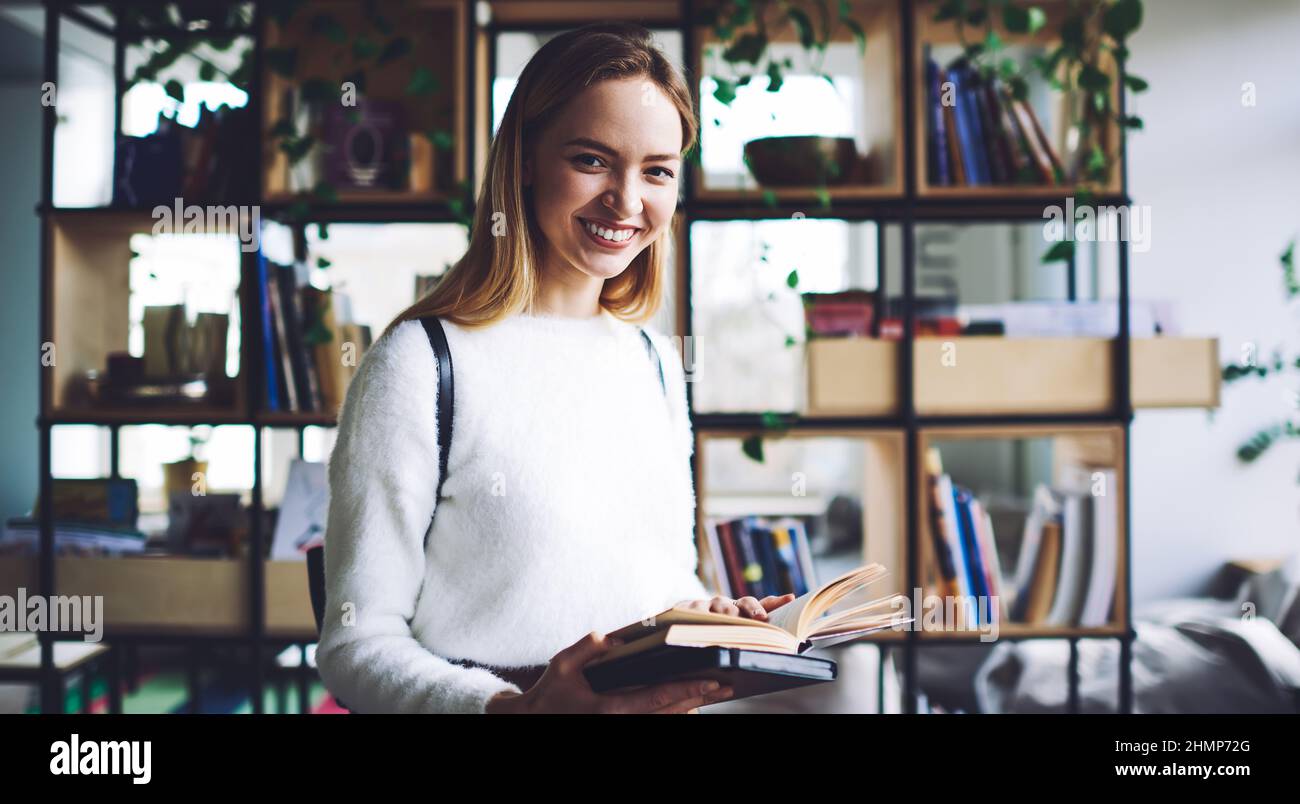 Un adolescent heureux lisant le livre dans la bibliothèque Banque D'Images