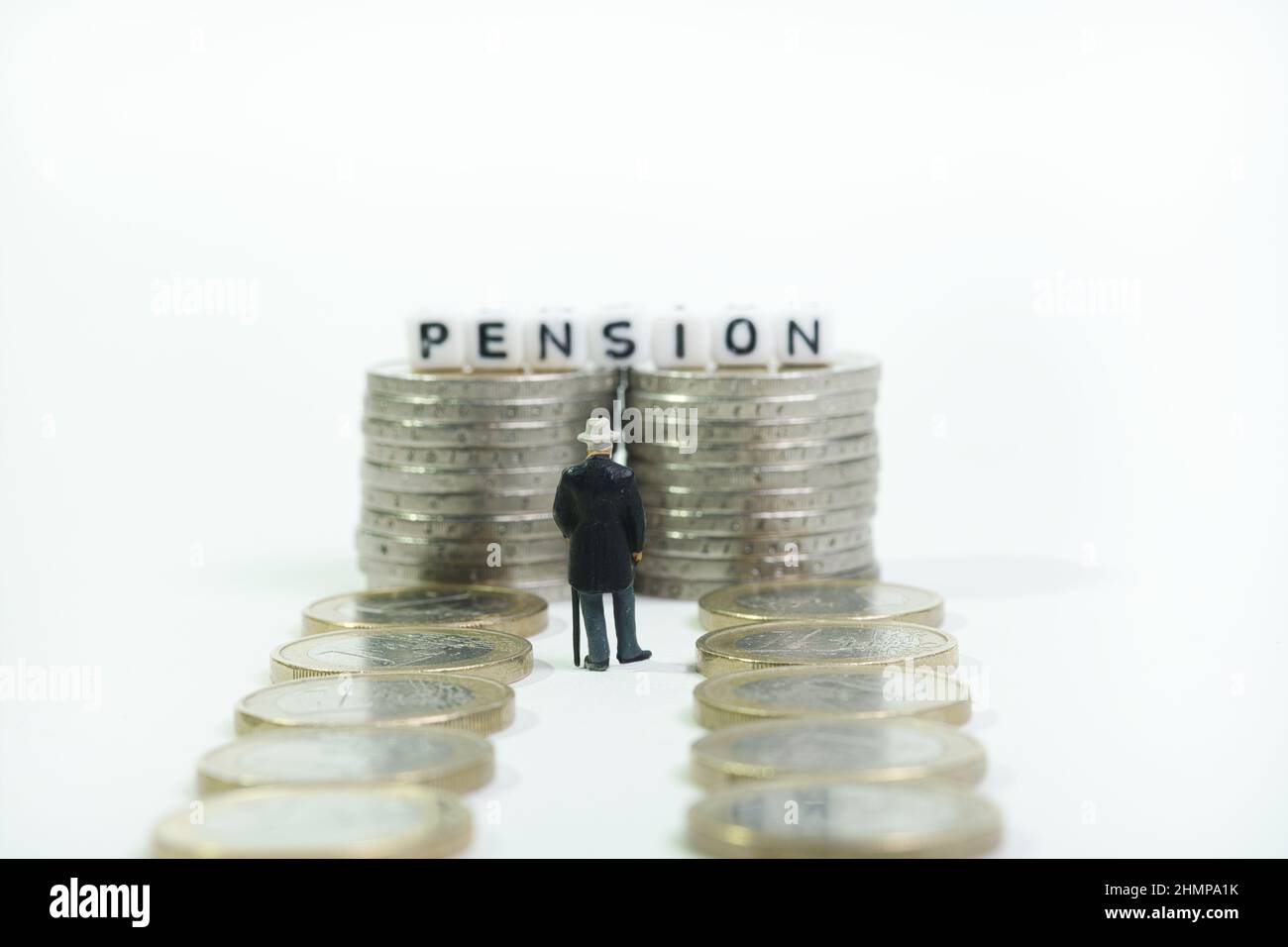 Un pensionné se tient devant des tours à pièces avec la pension d'inscription à la fin d'un chemin à pièces. Vue arrière, concept: Le long chemin de la retraite Banque D'Images