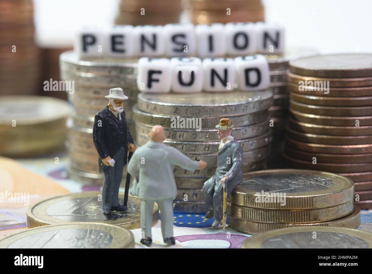 Un groupe de retraités se tient devant des piles de pièces avec l'inscription Caisse de retraite Banque D'Images