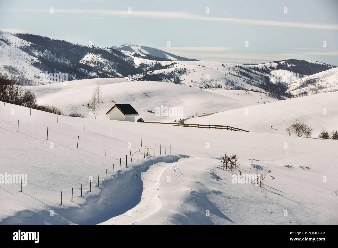 Hiver idyllique avec petite cabane sur la station de montagne Zlatibor, Serbie, Europe et route dans le paysage rural. Centre de ski de Tornik au loin Banque D'Images