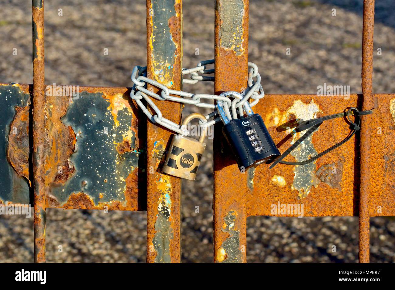 Gros plan des chaînes et des deux cadenas fixant une paire de portes métalliques rouillées dans une usine abandonnée, une clé de type Yale et une serrure combinée ASEC. Banque D'Images