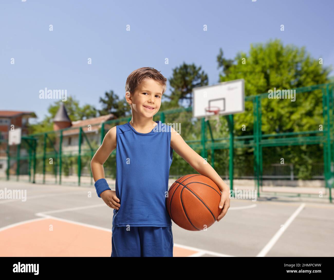 Garçon dans un jersey bleu tenant un basket-ball sur un terrain de basket-ball extérieur Banque D'Images