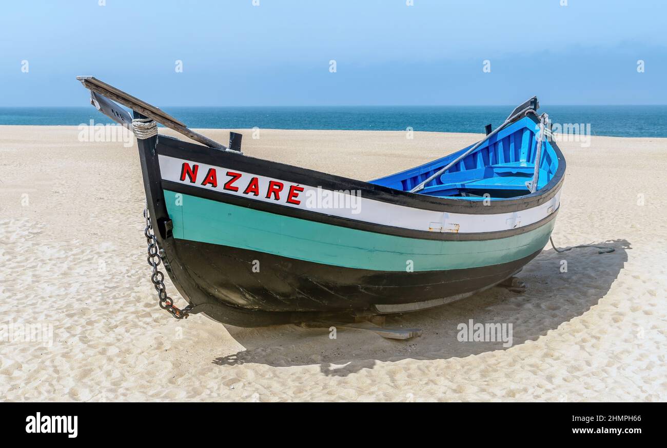 Nazaré, Portugal - avril 2018: Vieux bateau de pêche traditionnel coloré en bois sur la plage du village de pêcheurs de Nazaré. La haute falaise de Nazaré Sitio Banque D'Images