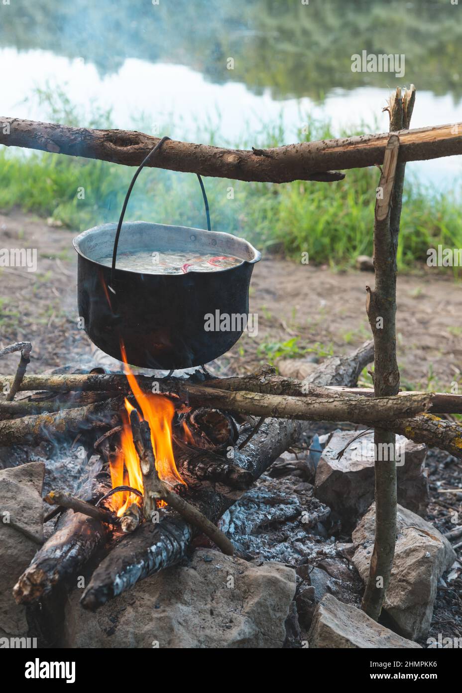 Faire cuire une soupe de poisson dans une casserole au feu sur la rive de la rivière le jour d'été Banque D'Images