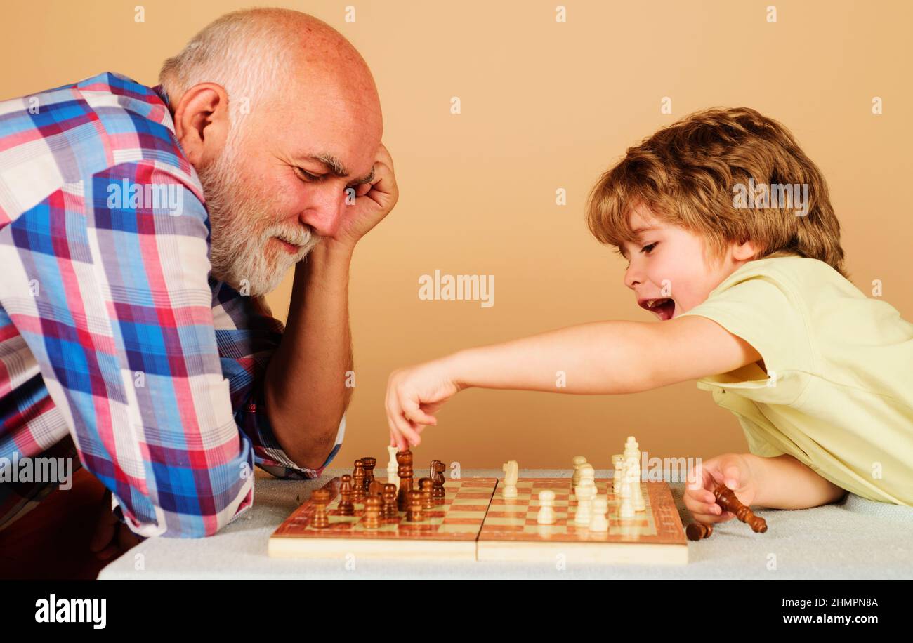 Joyeux gamin jouant aux échecs avec grand-père. Relations familiales avec le grand-père et le petit-fils. Jeu de société. Banque D'Images