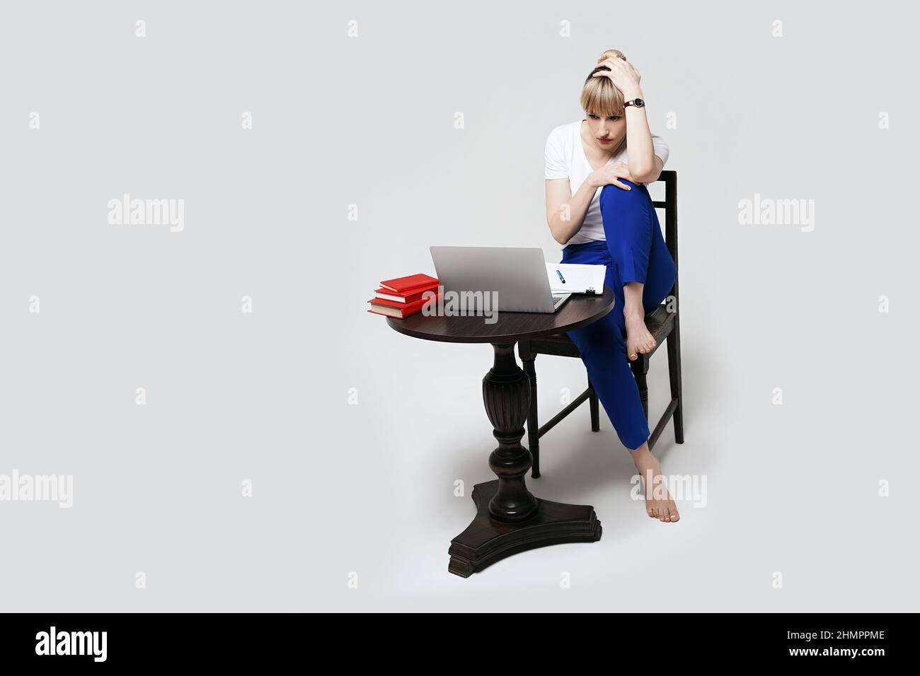 Jeune étudiante concentrée assise au bureau travaillant ou étudiant à distance en ligne écrivant des notes tout en regardant sur l'écran d'un ordinateur portable. Apprentissage à distance ou Banque D'Images