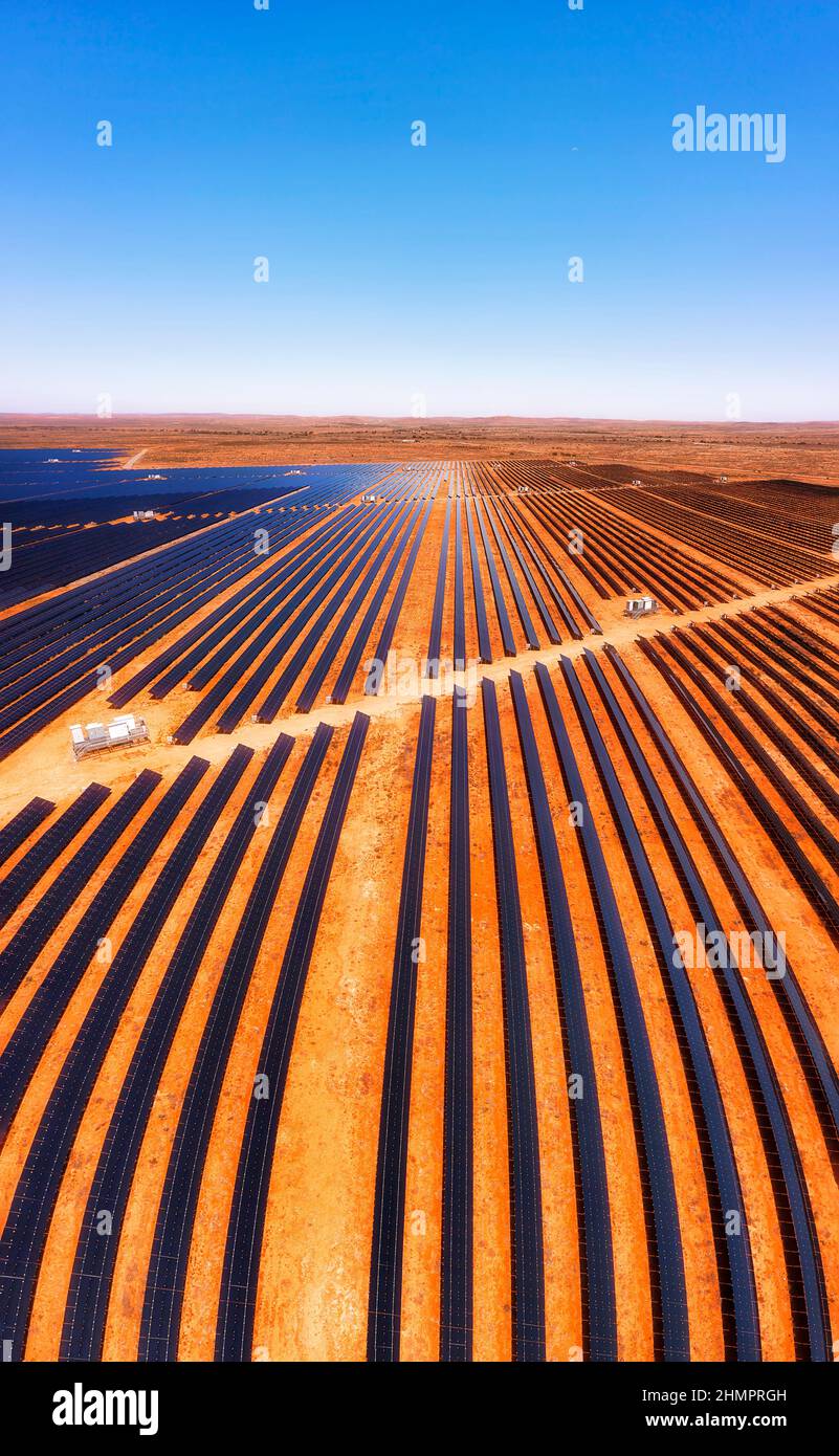 Lignes verticales d'éléments de panneau solaire à l'usine solaire de Broken Hill sur sol rouge dans l'Outback australien - vue aérienne. Banque D'Images