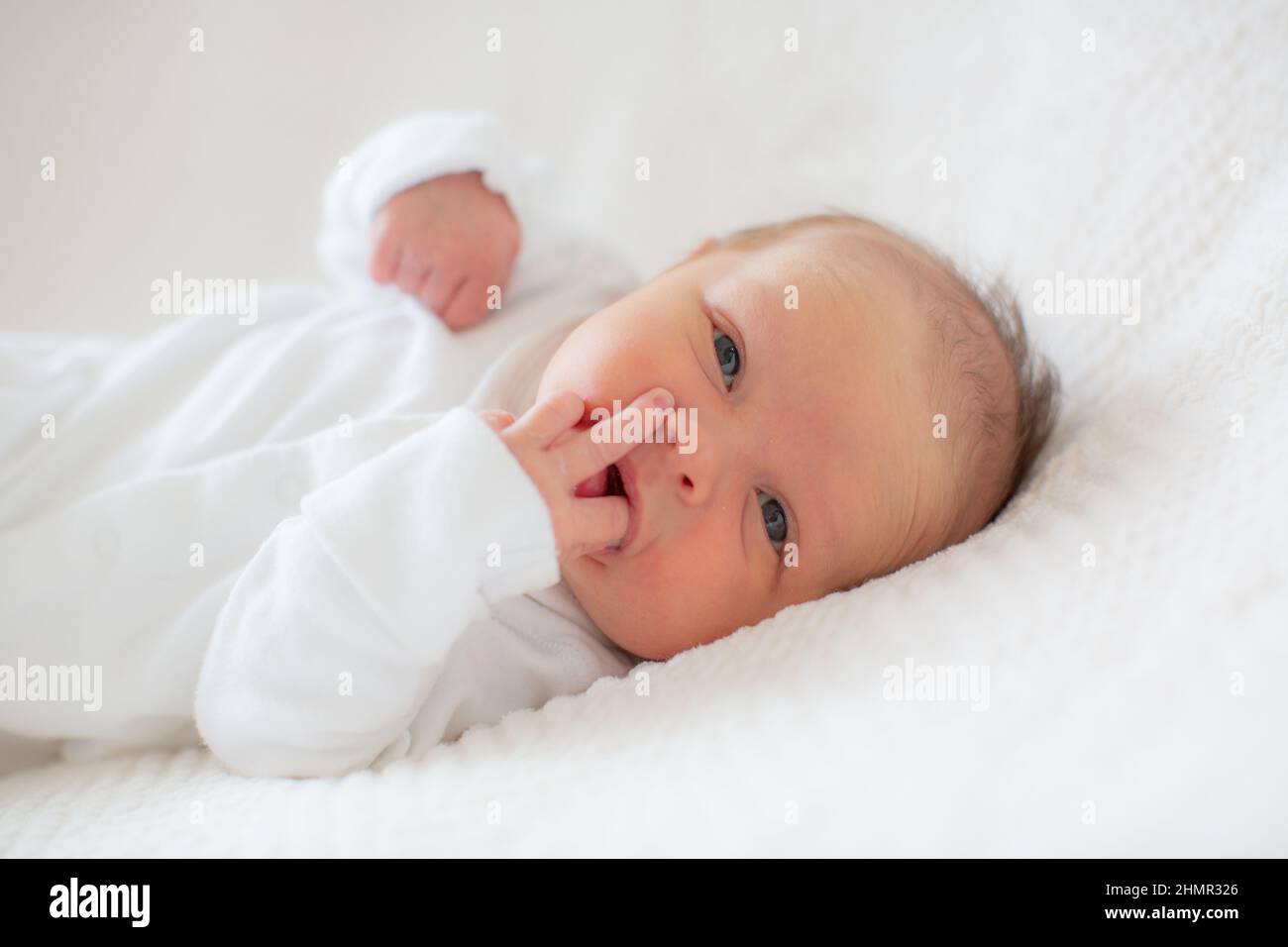 Portrait d'un bébé dans un babygro blanc sur fond blanc. Banque D'Images