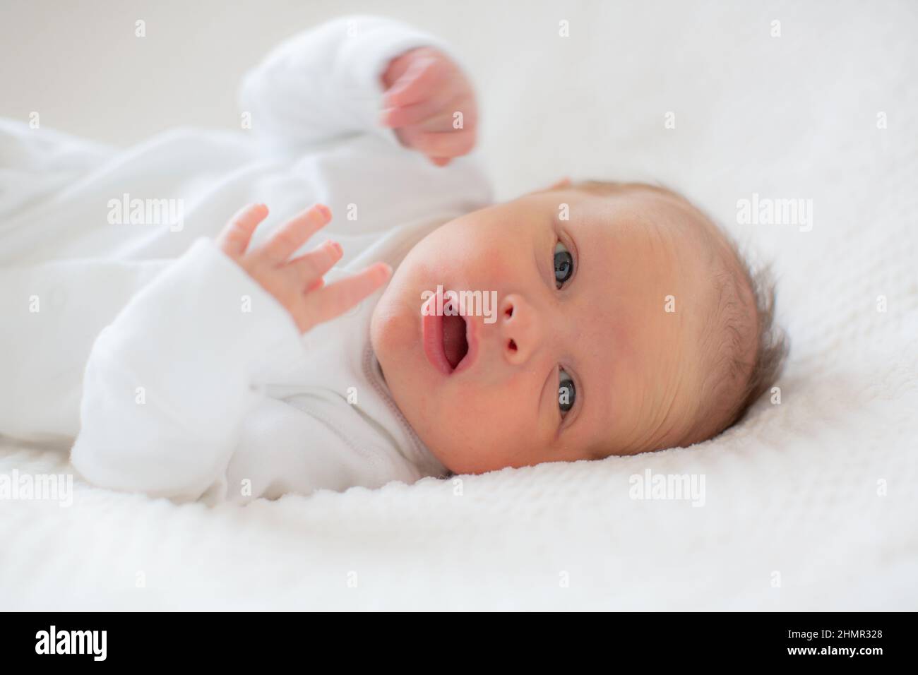 Portrait d'un bébé dans un babygro blanc sur fond blanc. Banque D'Images