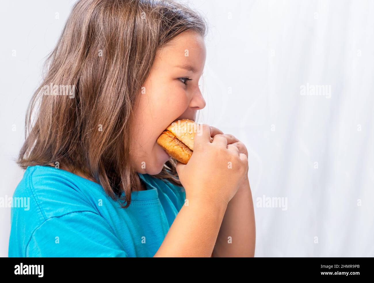 Une fille qui a faim mange du hamburger avec plaisir Banque D'Images