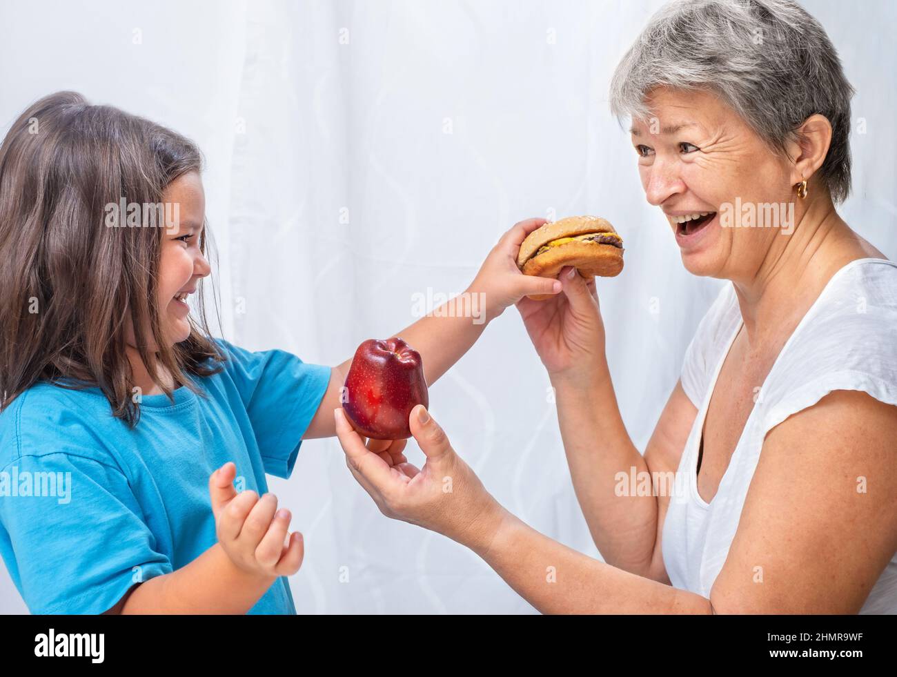 Grand-mère offre à son enfant une pomme au lieu d'un hamburger pour un mode de vie sain Banque D'Images