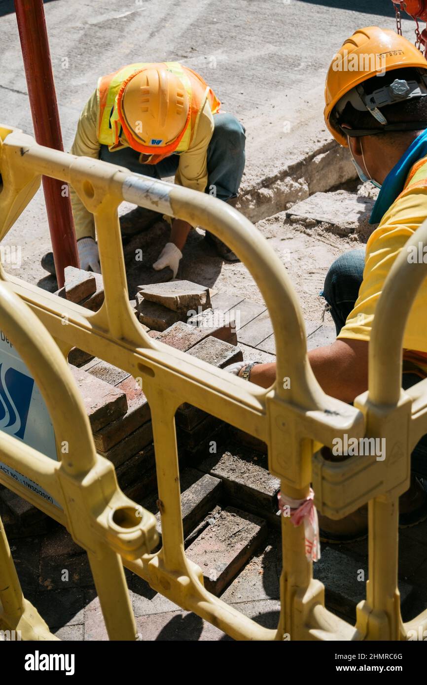 Ouvriers de la construction avec des casques de sécurité derrière la clôture en plastique Banque D'Images