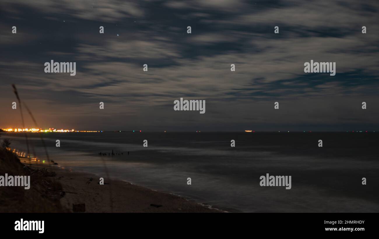 les étoiles derrière les nuages et la surface calme de l'eau par la mer à la recherche de la réflexion des lumières du nord Banque D'Images