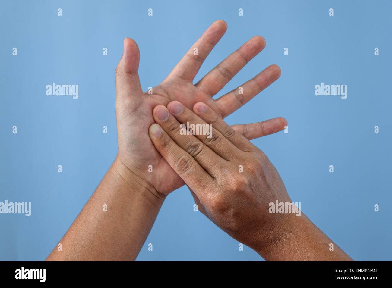 Concept de syndrome de bureau. Les mains sont massées après avoir travaillé avec les doigts. Gros plan isoler sur fond bleu. Banque D'Images