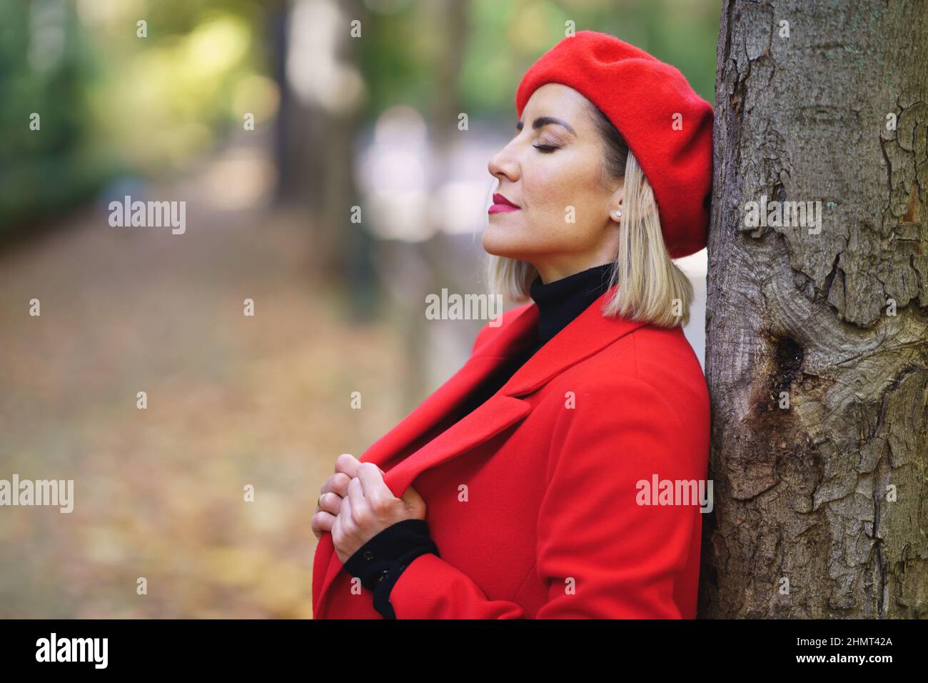 Femme rêveuse près d'un arbre dans un parc Banque D'Images